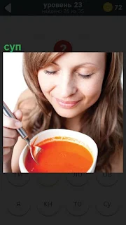 Девушка с удовольствием ест суп из тарелки ложкой