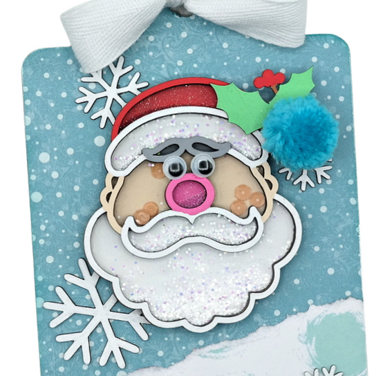 Chipboard Santa glitter and sequin filled shaker embellishment on a chipboard Christmas tag.