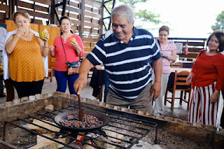 Un turista de la tercera edad sonríe mientras tuesta cacao, emocionado por hacer su propio chocolate.