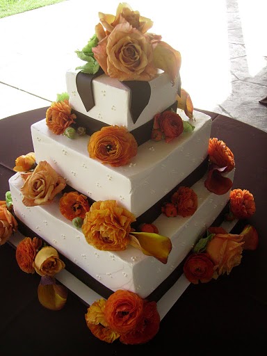 Round four tier white wedding cake with fresh roses in between the tiers in 