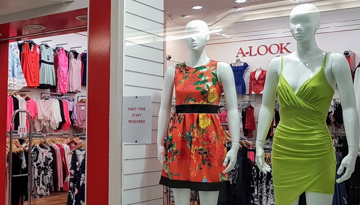 Shop window in a mall with two manequins wearing summer dresses in Irish colours