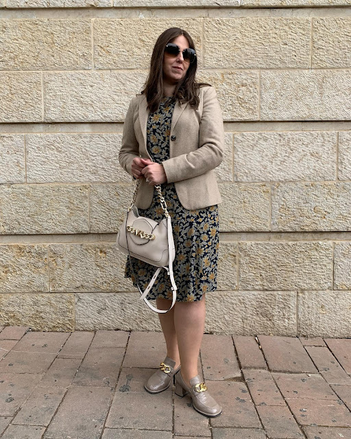 woman in neutrals standing against stone wall