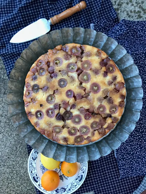 Top view of finished winter grape and citrus upside down cake on a cake stand.