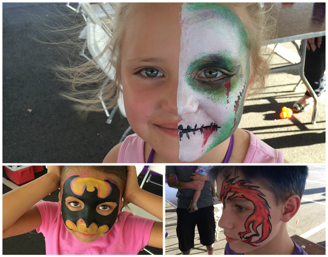 A few young kids with their faces painted like Zombies, Batman, and a Dragon