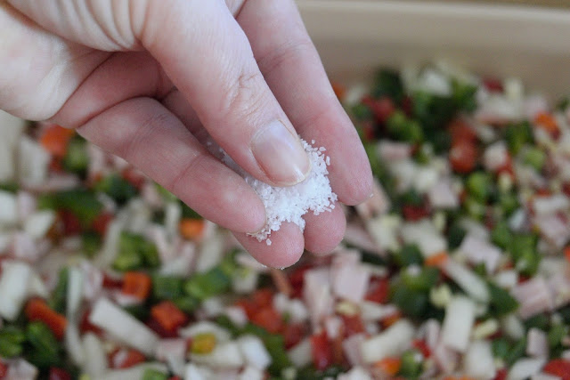 Salt being added to the ingredients in the casserole dish. 