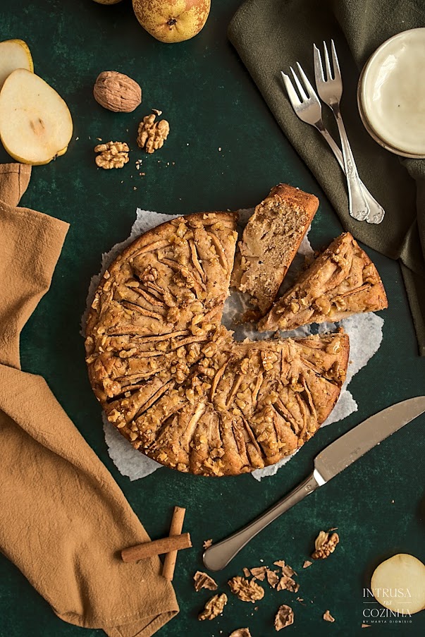 Bolo de Pera e Noz, num fundo verde escuro e duas fatias partidas