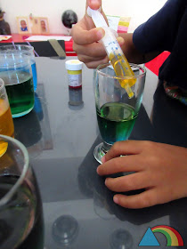 Añadiendo agua coloreada con azúcar a un vaso con la ayuda de una jeringuilla
