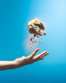 Image of a hand throwing a rock into the air.