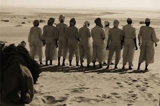 Bedouins pray together in the desert.