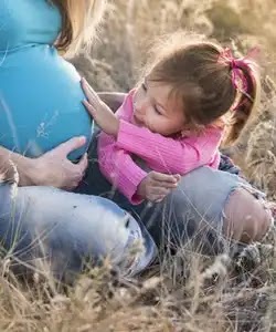 benefits of soy milk. A girl in a pink jacket and gray jeans touch the belly of a pregnant woman