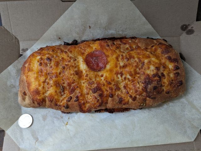 Domino's Pepperoni Stuffed Cheesy Bread top-down view next to a quarter.