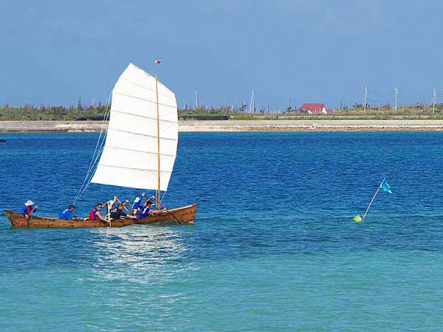 white sail and team paddling sabani boat