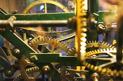 Clockwork including large golden cogs and green metalwork.