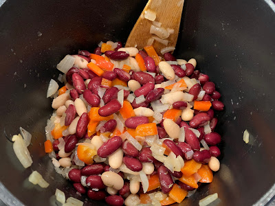 Beans, onion, red pepper and herbs in a saucepan