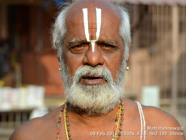 Matt Hahnewald Photography; Facing the World; closeup; street portrait; headshot; outdoor; Asia; South Asia; India; Tamil Nadu; Tiruchirappalli; Nikon D3100; Nikkor AF-S 50mm f/1.8G; travel; travel destination; Hindu; Hinduism; photography; colour; portraiture; person; people; eyes; face; Srirangam; Sri Ranganathaswamy Temple; eye contact; religion; Indian man; friendly; modern Indian man; white beard; earrings; Indian middle class; urdhva pundra; Vishnu sign; Vaishnavite devotee; Vaishnavite pilgrim; Vaishnavism; tilaka mark