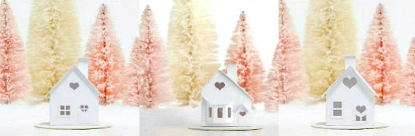 three tiny paper houses each with a heart shaped window surrounded by pastel colored bottle brush trees