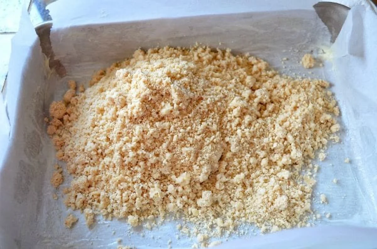 Almond Shortbread Crust dough poured into baking pan lined with parchment paper.