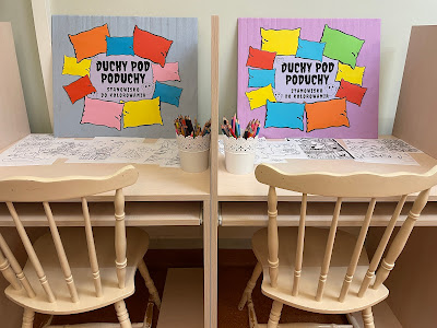Dwa stoliki z dosuniętymi krzesłami. Na stolikach kredki w pojemnikach, kolorowanki z duchami oraz napis" Duchy pod poduchy - stanowisko do kolorowania.