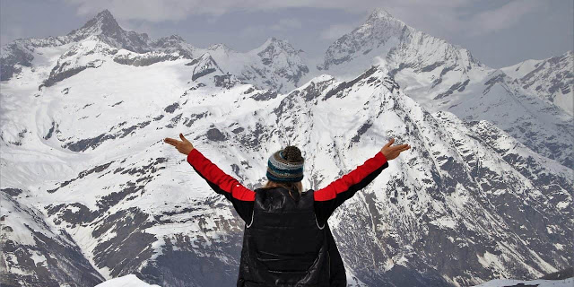 A woman climbs a snow mountain, wearing a heated vest.