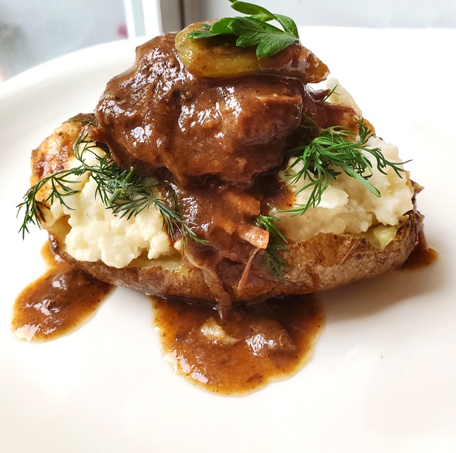 beef and gravy over a baked potato