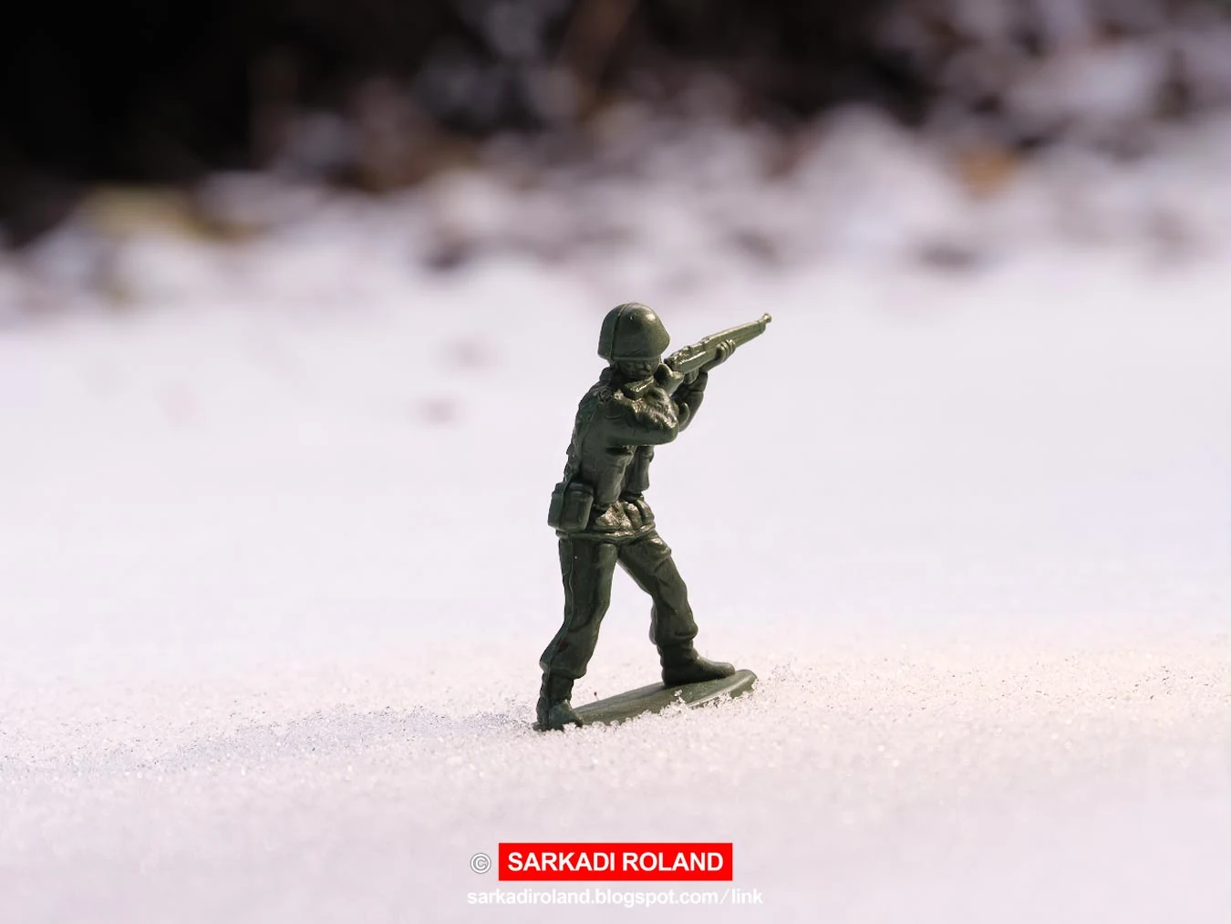 Hadijáték katona ragyogó nappal egy hideg, havas csatatéri tájon. Fagyott földhalmok, fák a homályos és sötét háttérben. - War toy soldier in bright daylight on a cold, snowy battlefield landscape. Frozen earth mounds, trees in the dim and dark background. Photo: © Sarkadi Roland copyright