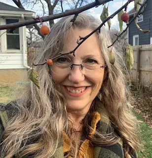 smiling woman standing under tree in yard