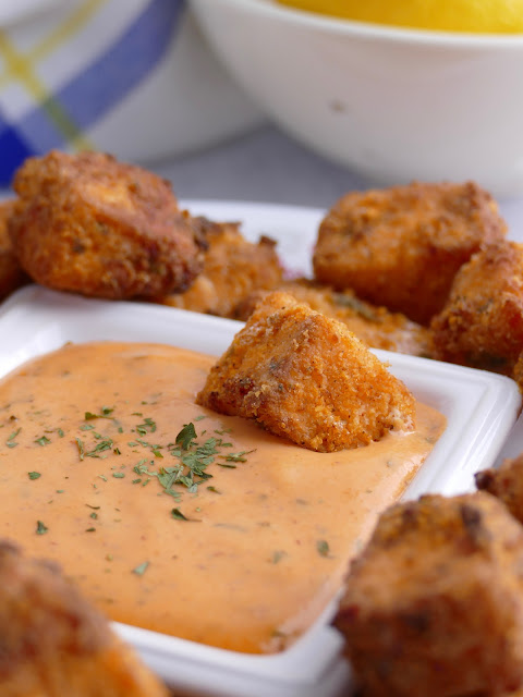 salmon nugget in dipping sauce in a white square bowl.