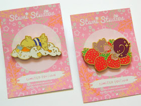 A photo showing two pin badges, one of a sleeping duck and the other of a squirrel eating strawberries