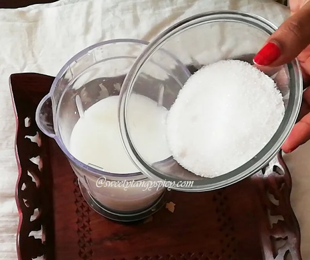 "Adding sugar to the lassi mixture."