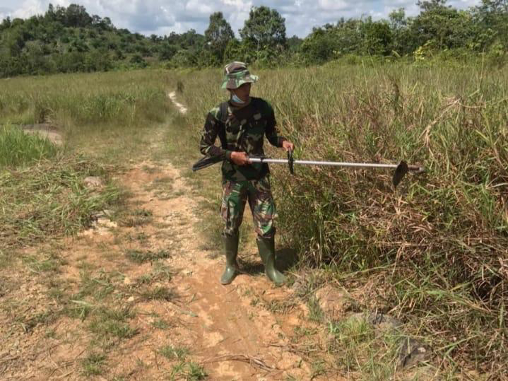 Anggota Satgas TMMD Membersihkan Area Kantor Desa