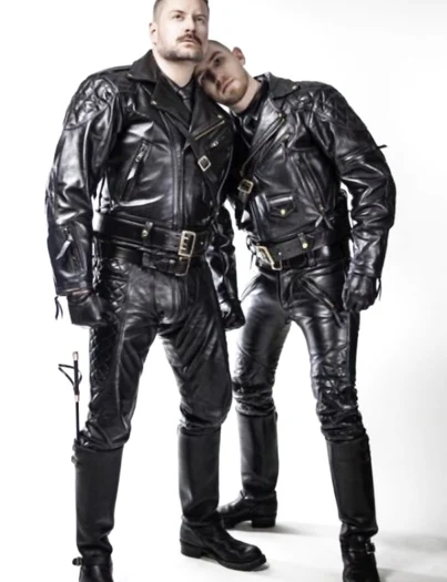 Two tall leather men wearing full black leather gear one with his head on the other shoulder