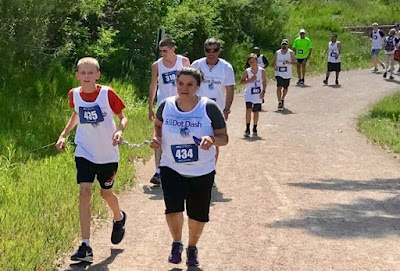  Blind and visually impaired runners, guides, and sighted runners along the Mary Carter Greenway Trail during the 1st annual NFBCO 6 Dot Dash 5K in 2018