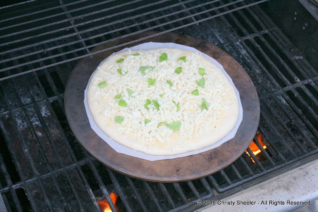 Cheesy pizza placed on the preheated pizza stone.