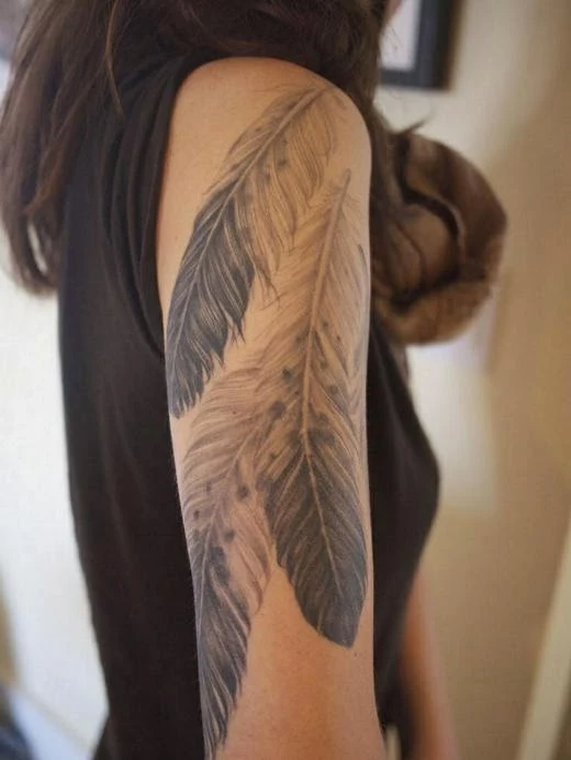 vemos una chica con un tatuaje en su brazo, el tatuaje de plumas le cubre media manga