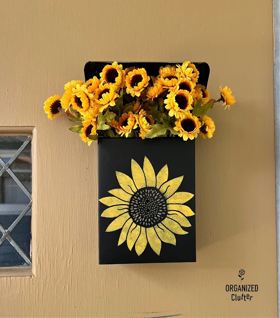 Photo of a black metal mail box stenciled and filled with sunflowers.