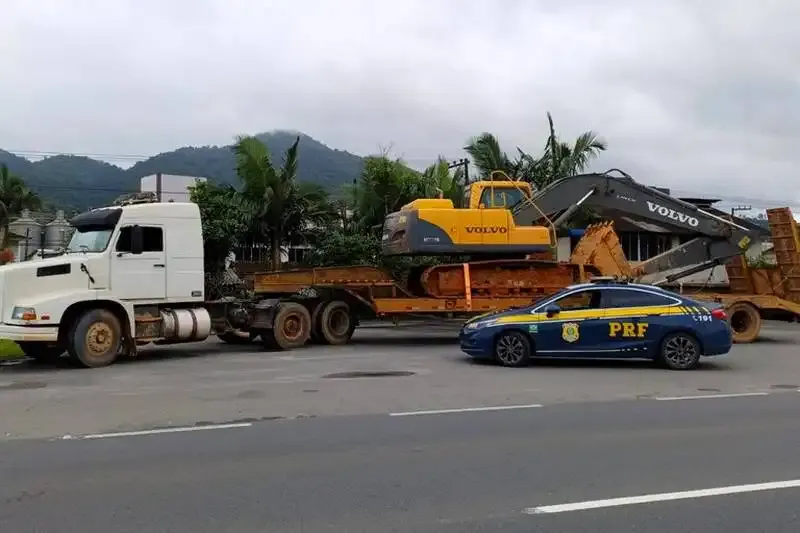 Viatura da PRF ao lado de carreta com escavadeira