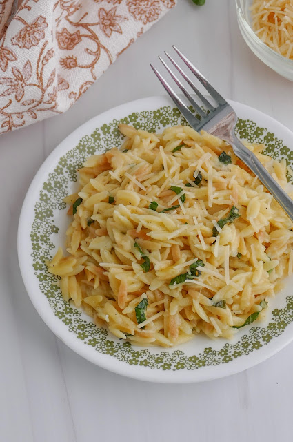 Parmesan Orzo on a white and green plate with a fork on the side.