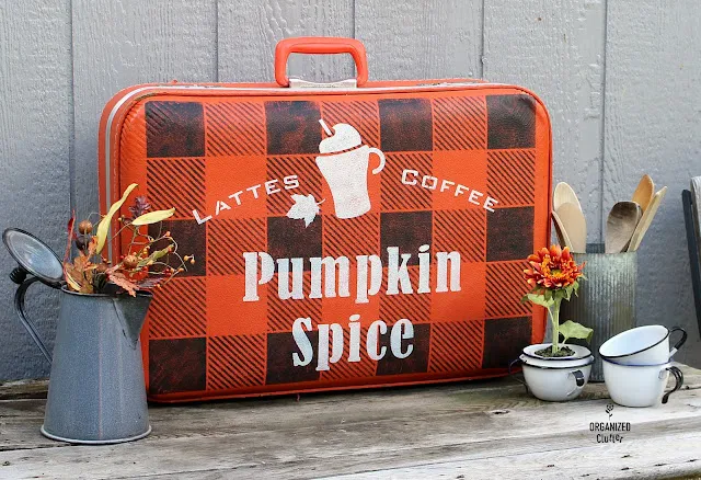Photo of an orange garage sale suitcase stenciled as fall decor.