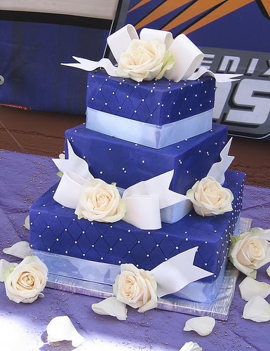 Dark purple wedding cake with white roses white bows and quilted tiers