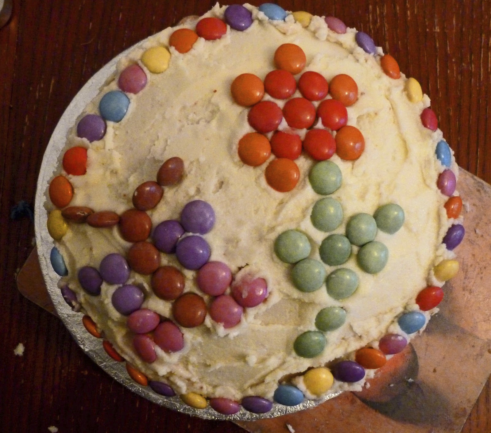 Photo of a Smartie cake, the top is decoprated with a flower and butterfly in a Smartie mosaic.