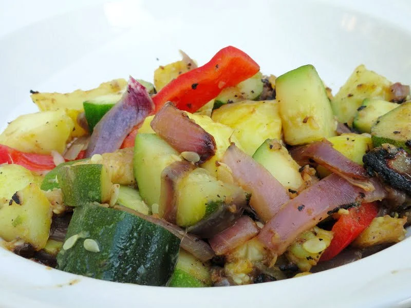 Zucchini, Summer Squash, Red Bell Pepper with Ginger and Garlic cooked and served in a white bowl.