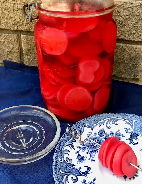 Jar filled with quick pickled red radishes with a five radish slices on a plate.