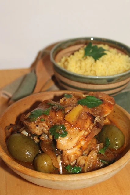 Serving bowl of Chicken with preserved lemons and olives and saffron couscous.