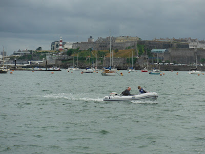 Small dinghy racing across body of water with city in background