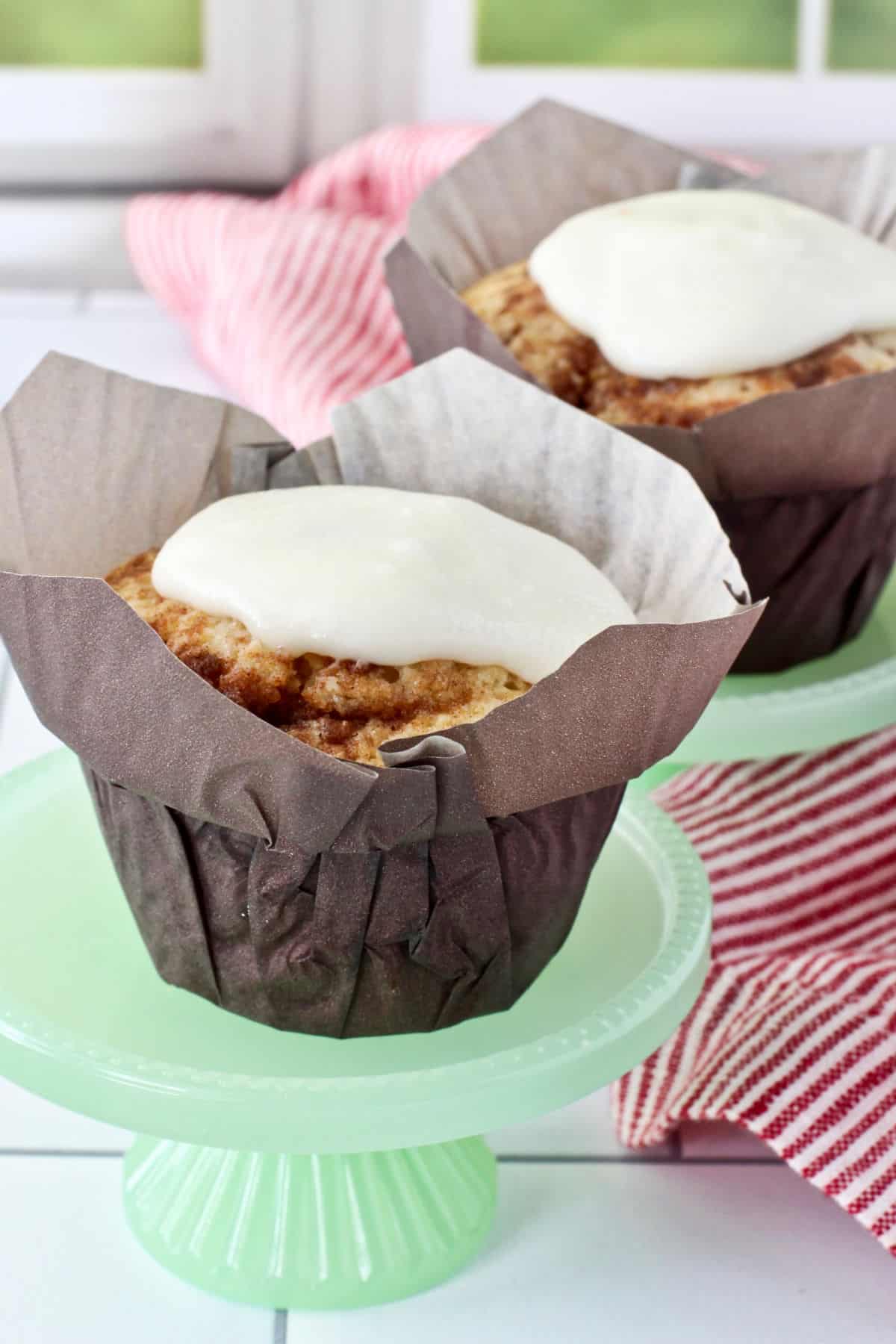 Cinnamon Roll Muffins in a brown wrapper with icing.