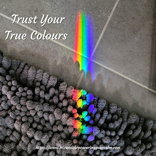 A strong rainbow prism reflected through a window  onto a grey tiled floor with the wording: Trust Your True Colours