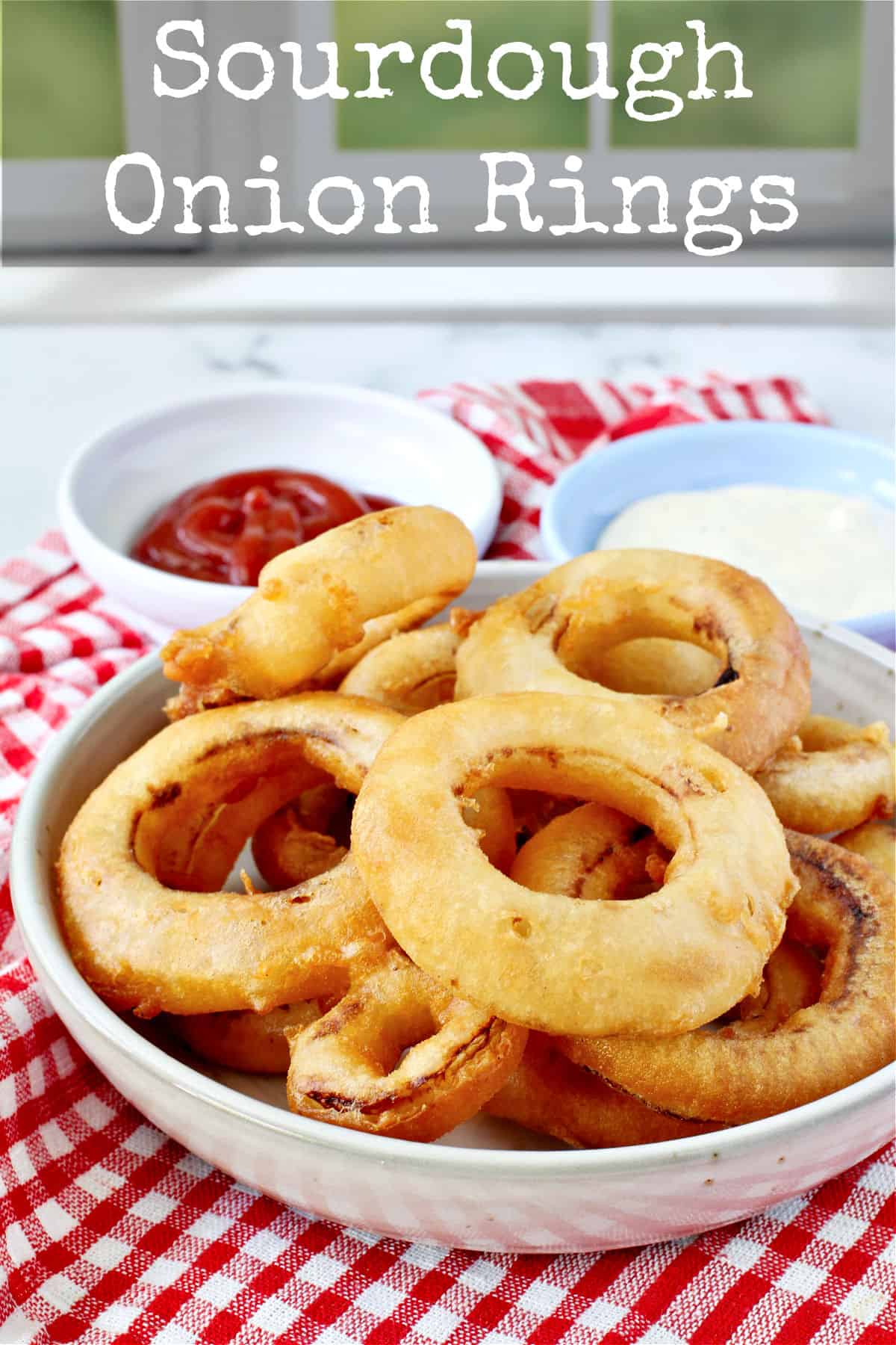 Three-Ingredient Sourdough Onion Rings in a bowl with dipping sauces.