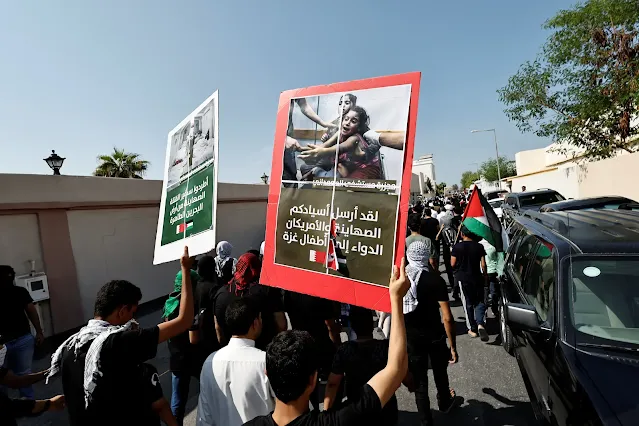 متظاهرون يحملون صورًا لتداعيات هجمات غزة أثناء مسيرتهم خلال مسيرة لدعم الفلسطينيين في البحرين