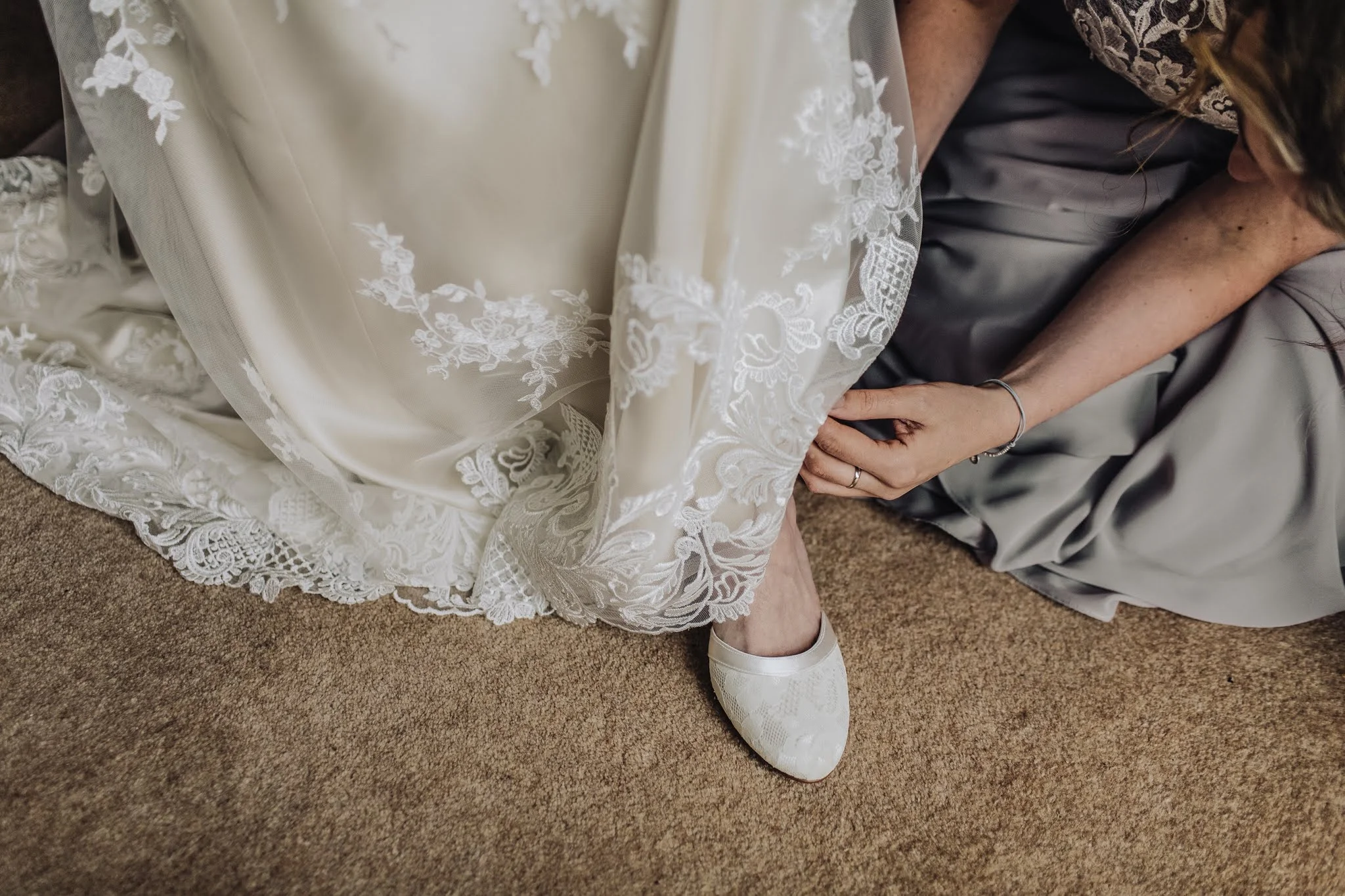 maid of honor helps bride to put on her heels