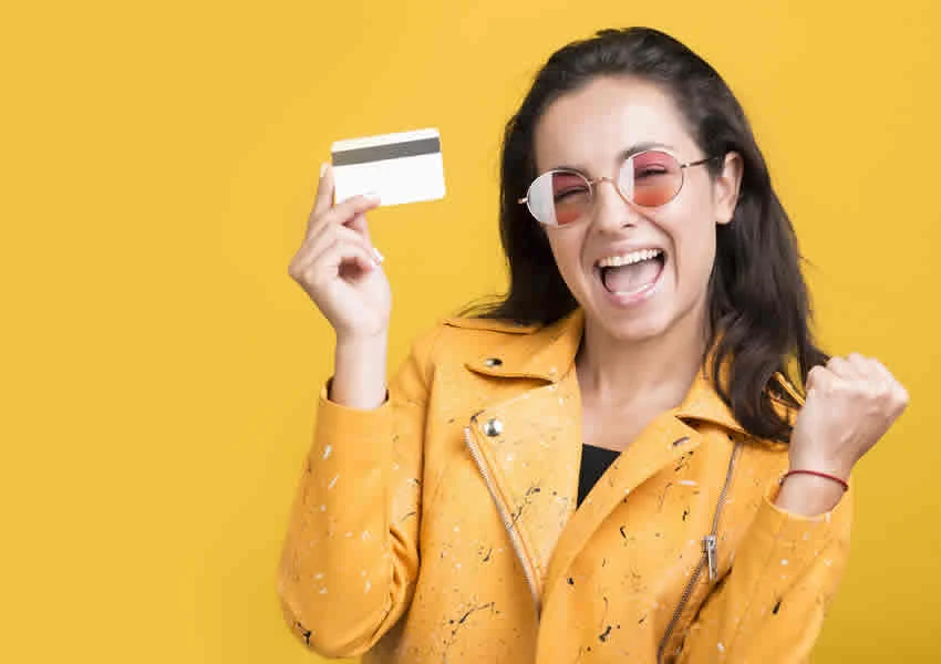 Mulher sorrindo segurando um cartão de crédito trigg.